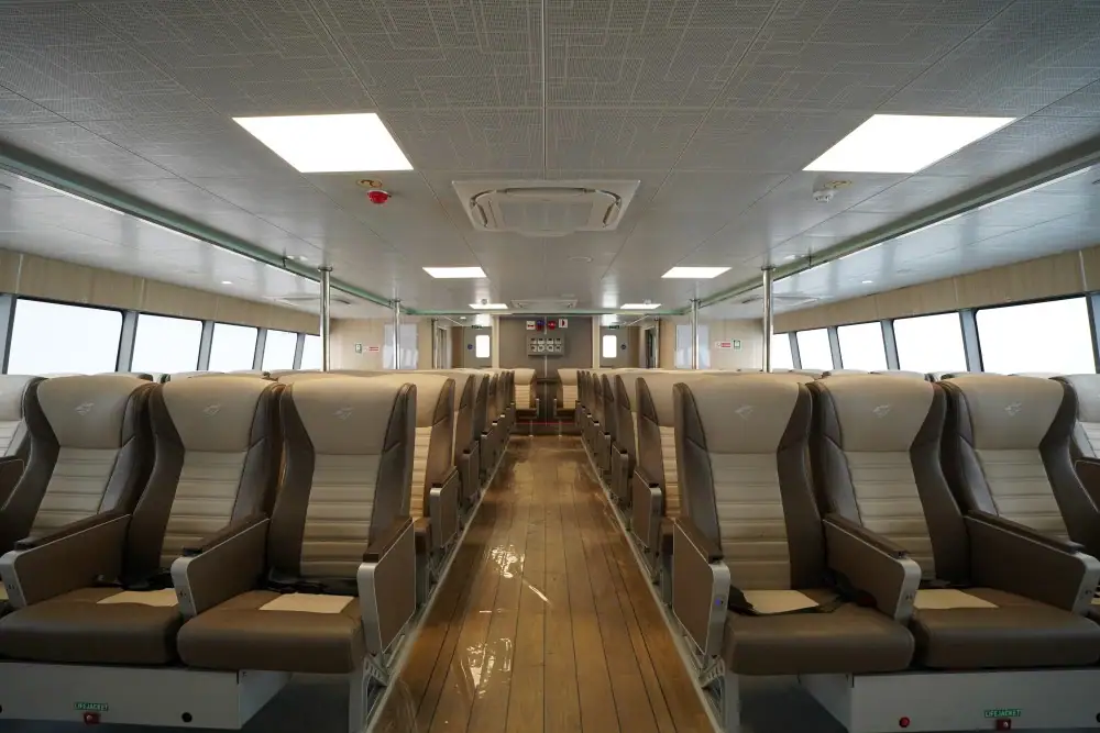 Passenger seats inside Ashi Ferry with large windows and wooden flooring.