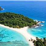 Pristine beach landscape of Cinque Island surrounded by clear sea and tropical vegetation
