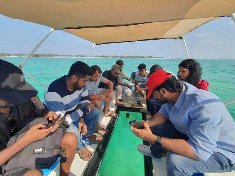 Tourists enjoying glass bottom boat ride over clear blue waters in Andaman.