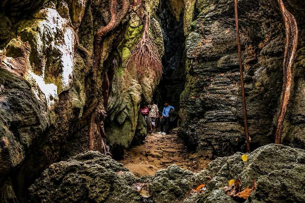 Exploring the narrow limestone cave passage in Andaman with tourists.