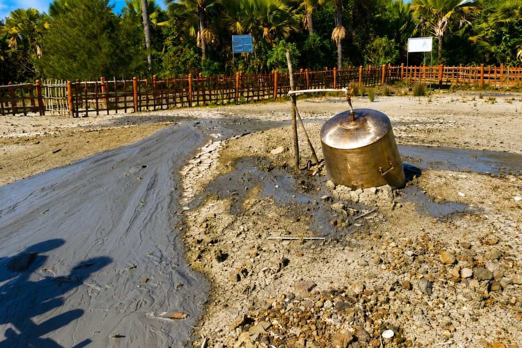 Mud volcano with bubbling mud and surrounding greenery in Andaman.