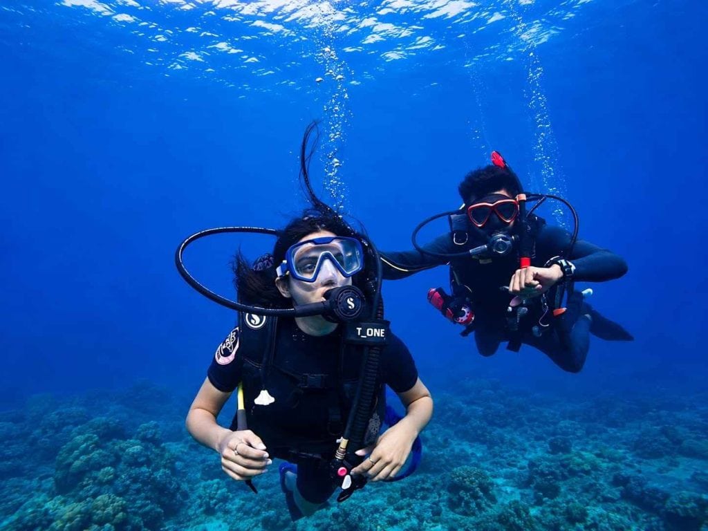 Two divers exploring coral reefs in Havelock, Andaman with scuba gear.