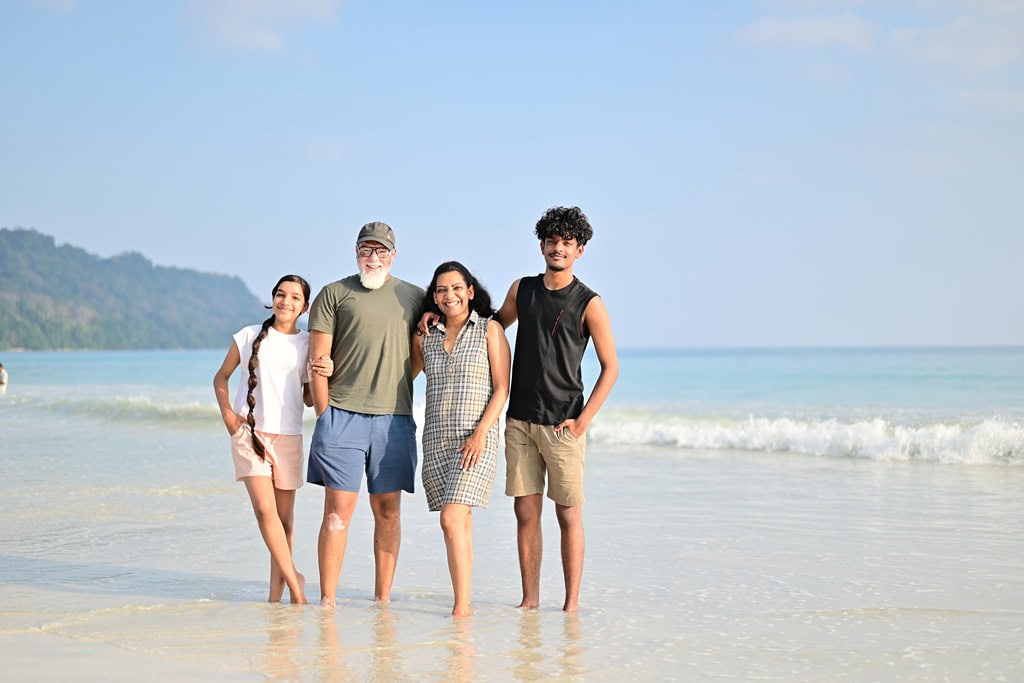 Family of four on the beach in Andaman with ocean and sky background.