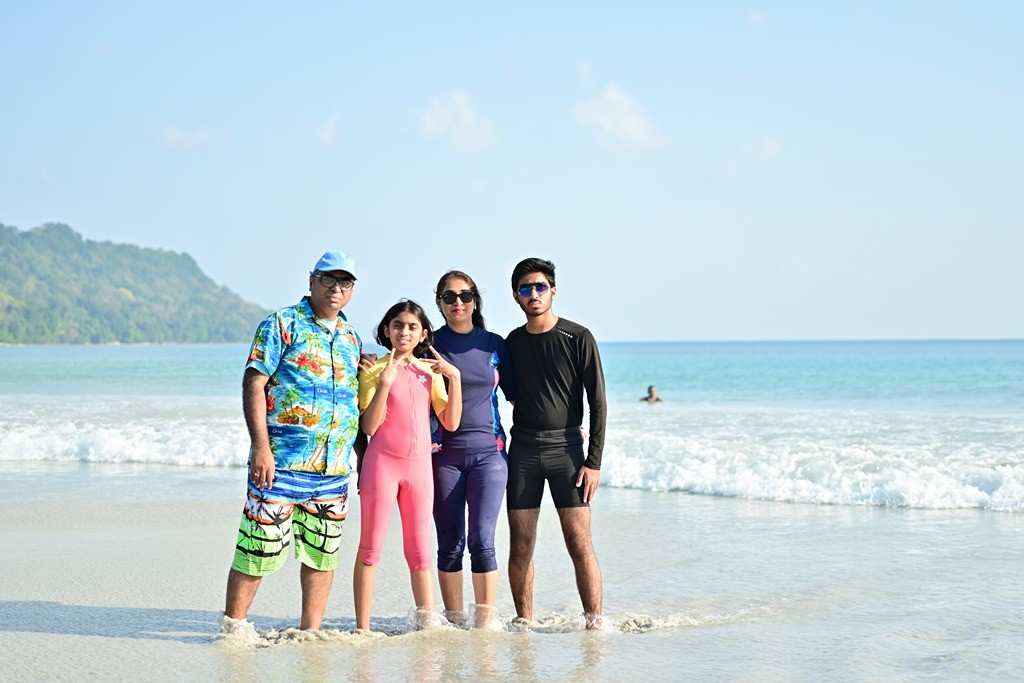 Family standing in shallow water at Andaman beach with scenic background.