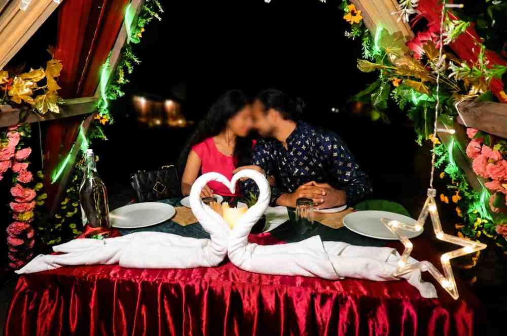 Couple enjoying a romantic dinner at sunset on Andaman beach with decorated table.