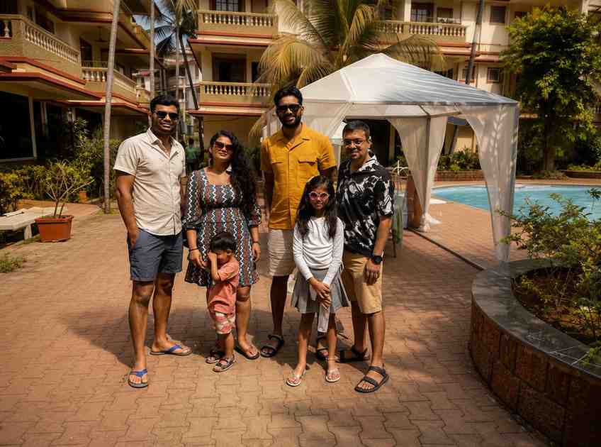 Family group at Andaman Ocean Tours & Travels resort with pool and palm trees.