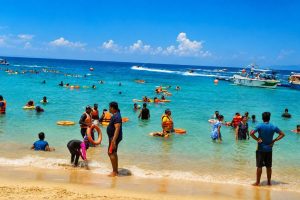 Tourists enjoying the clear waters and sandy beach in Andaman Islands.