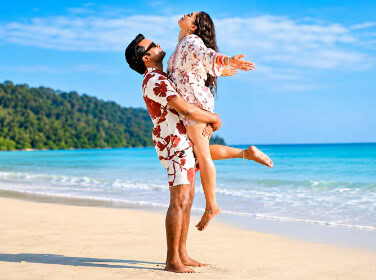 Happy couple enjoying beach day in Andaman with clear blue sky and ocean.