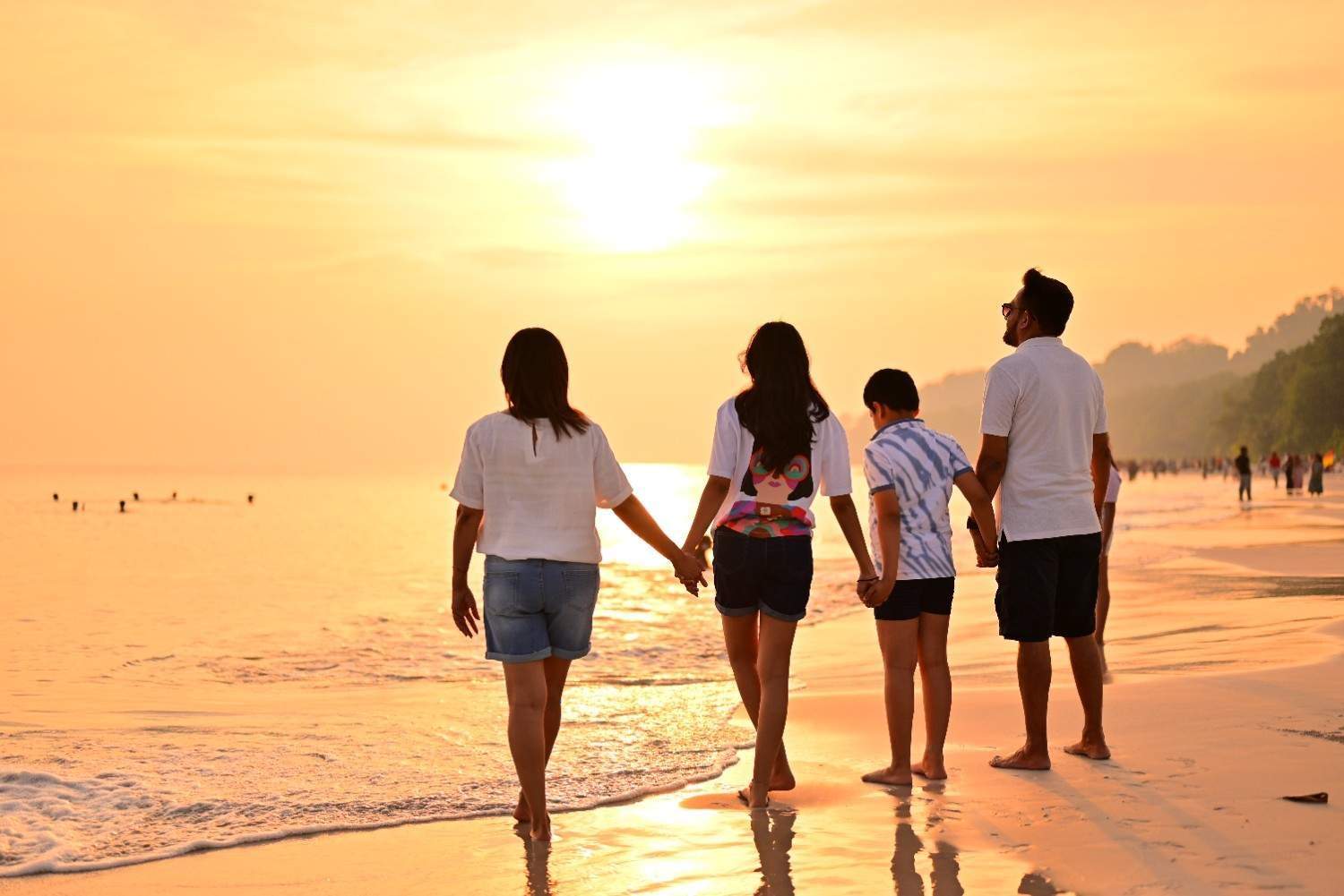 Family walking on the beach during sunset in Andaman Islands.