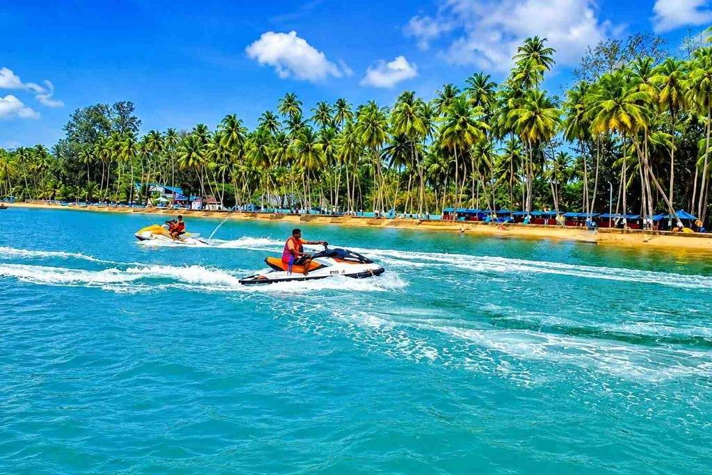 Jet skis on clear blue water with palm trees in the background.