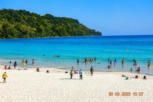 Beautiful beach in Andaman with turquoise water and green hills in the background.