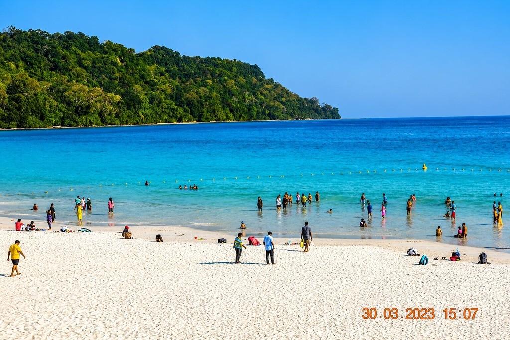 Beautiful beach in Andaman with turquoise water and green hills in the background.